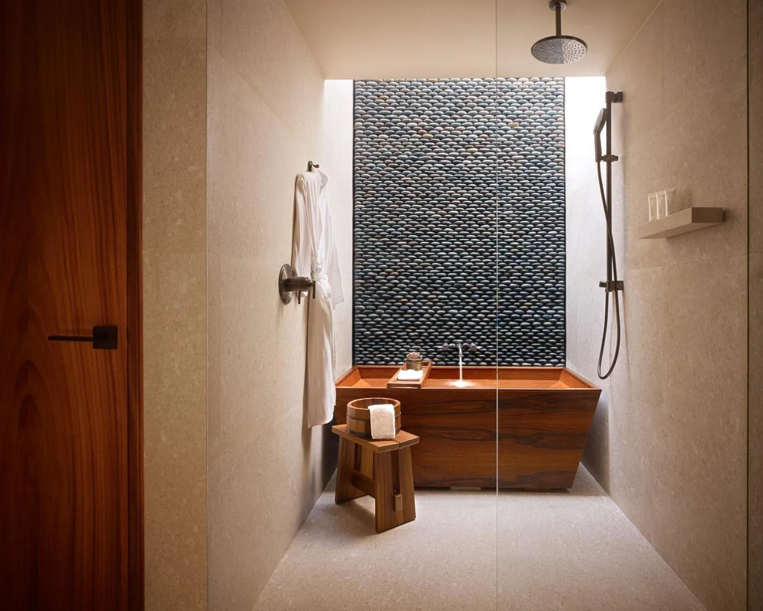 Deluxe bathroom wet room with rain shower, robe, stool, and wood tub at Nobu Hotel Los Cabos.