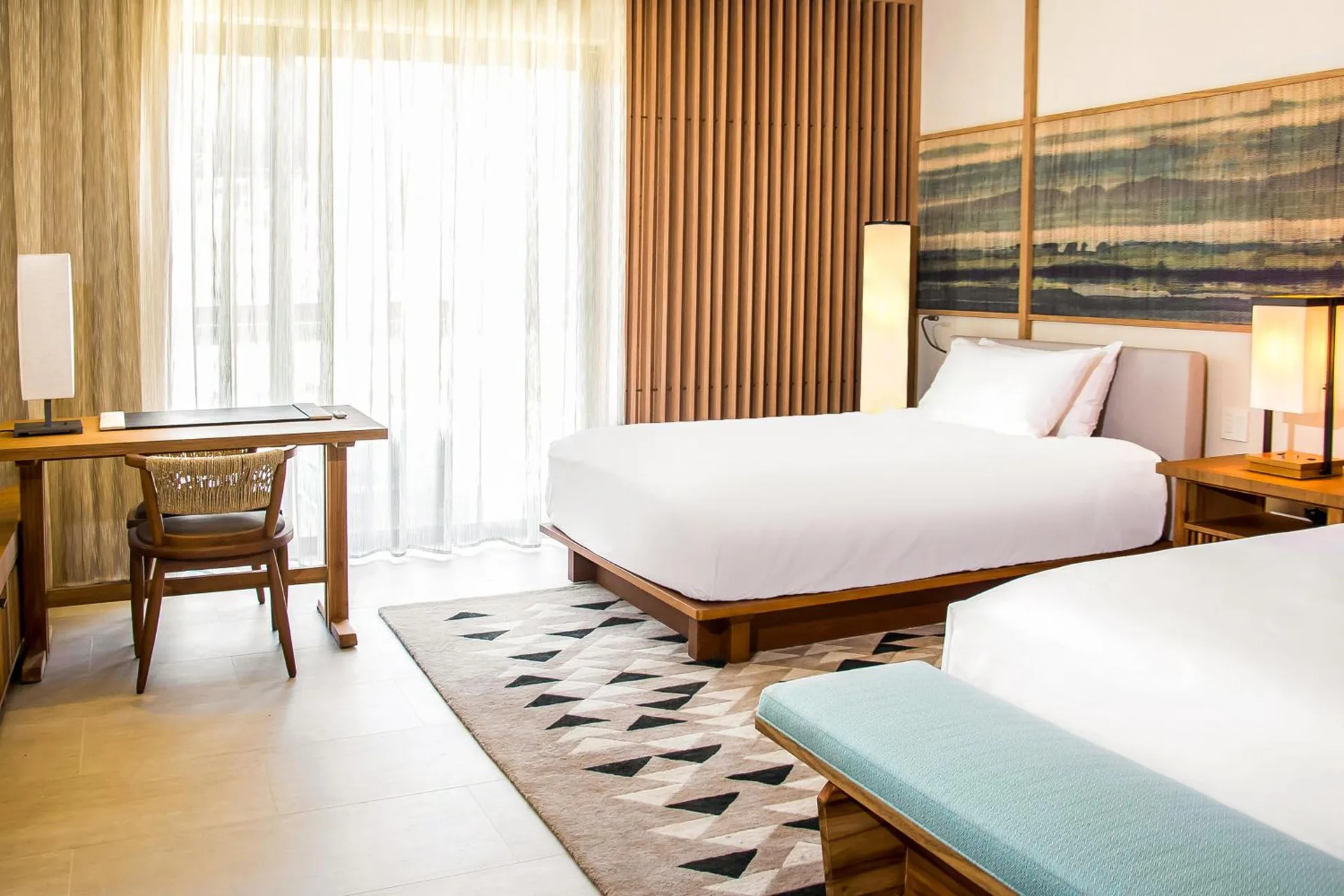 Deluxe room with two beds, desk, sheer curtains, and wall art at Nobu Hotel Los Cabos.
