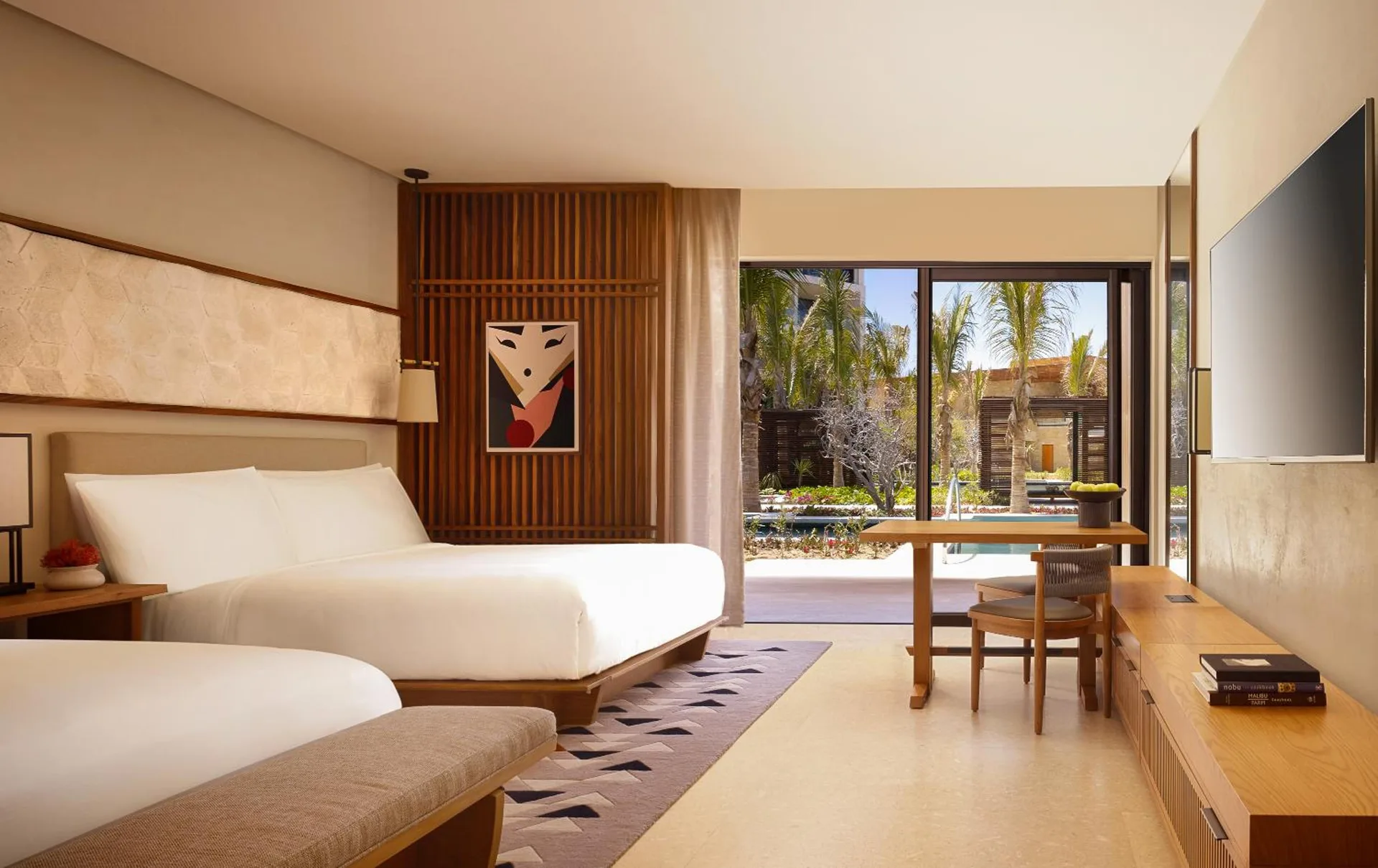 Deluxe room with two beds, desk, terrace doors, and garden view at Nobu Hotel Los Cabos.