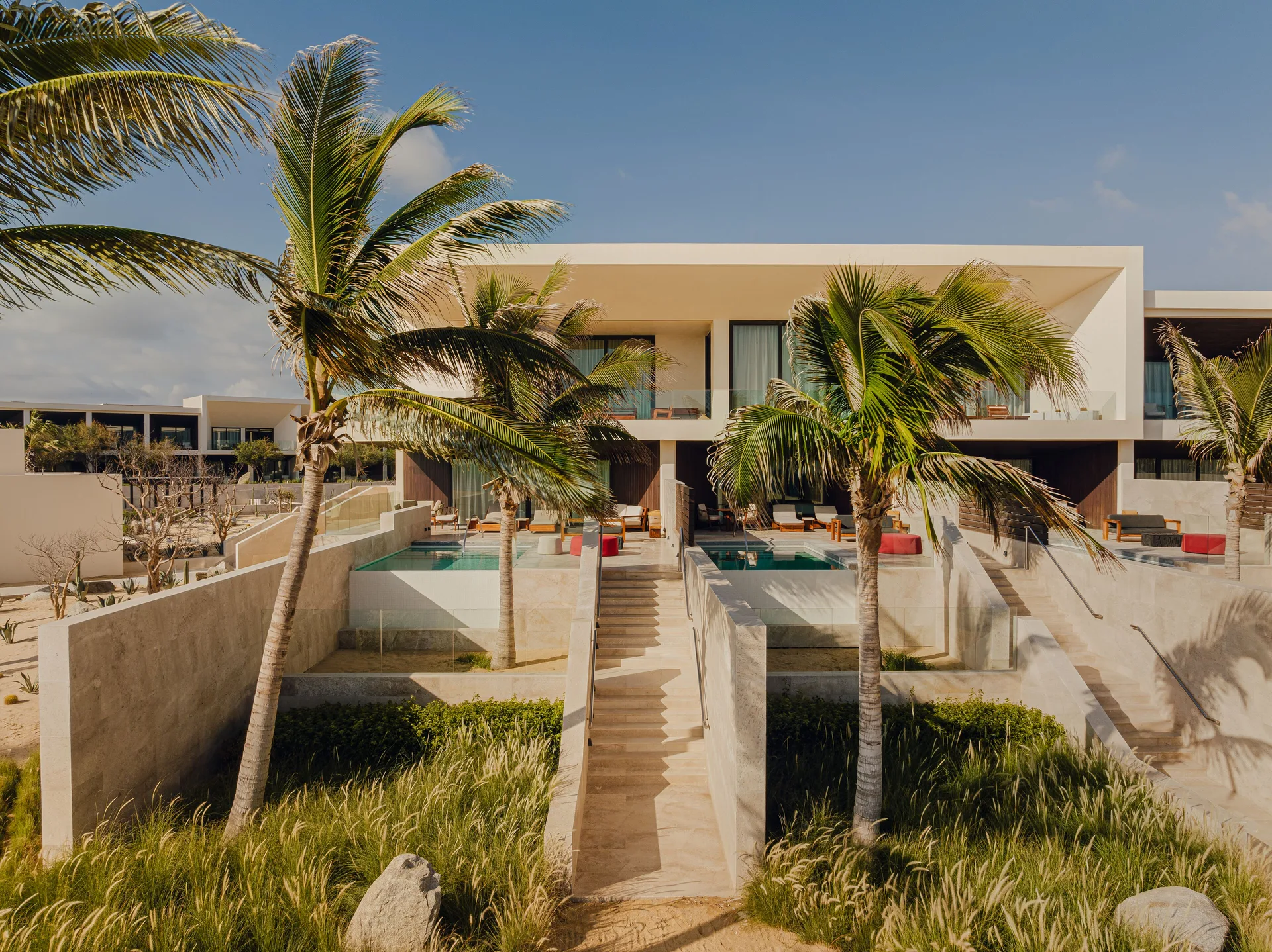 Oceanfront junior room buildings at Nobu Hotel Los Cabos with private pools and palm-lined paths.