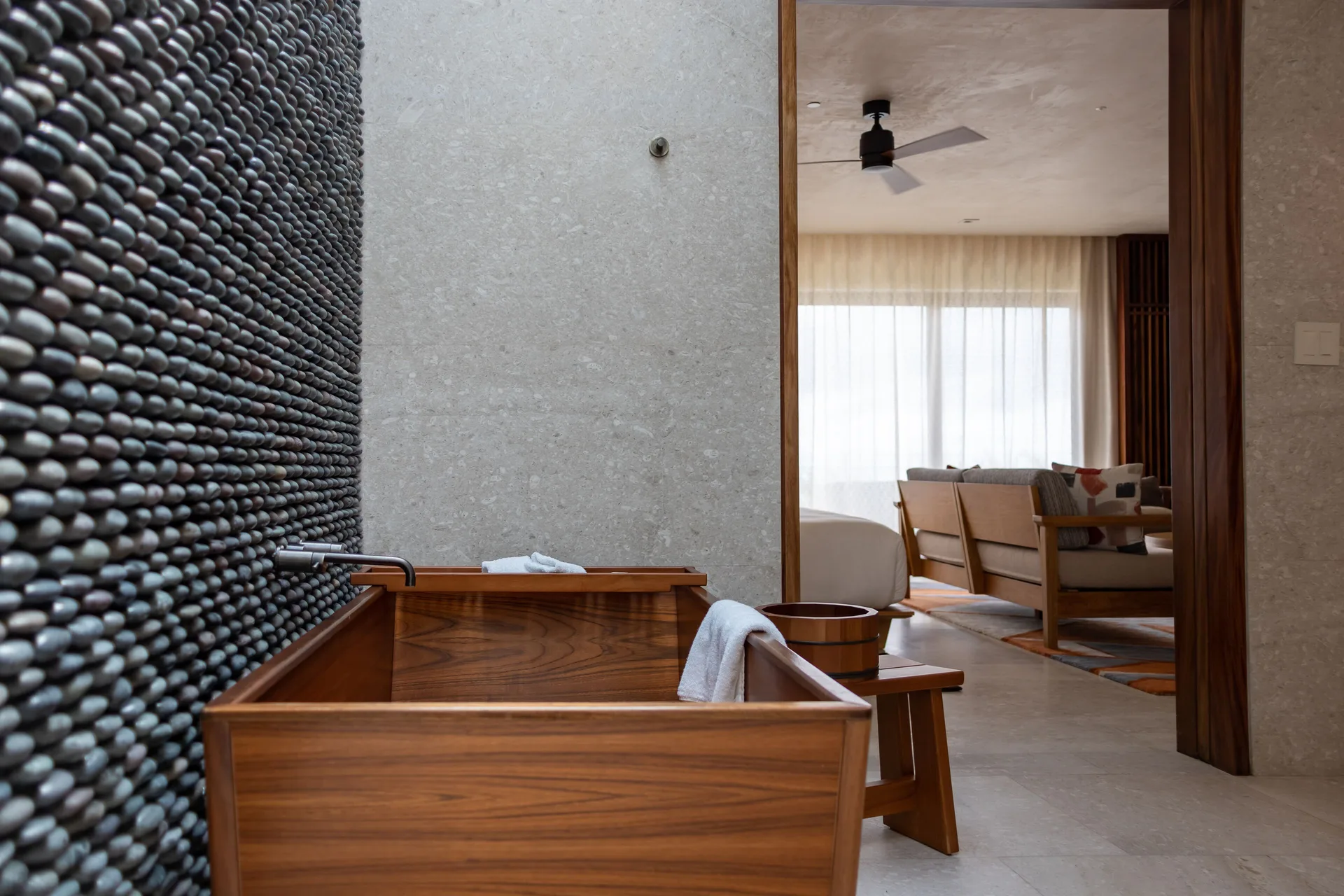Wooden soaking tub in an oceanfront junior room at Nobu Hotel Los Cabos, with the living area beyond.