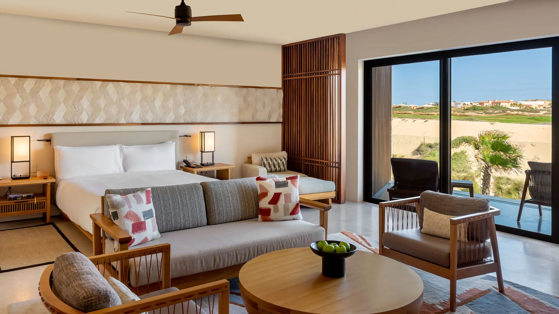 Junior Room king bed and seating area beside balcony doors at Nobu Hotel Los Cabos.
