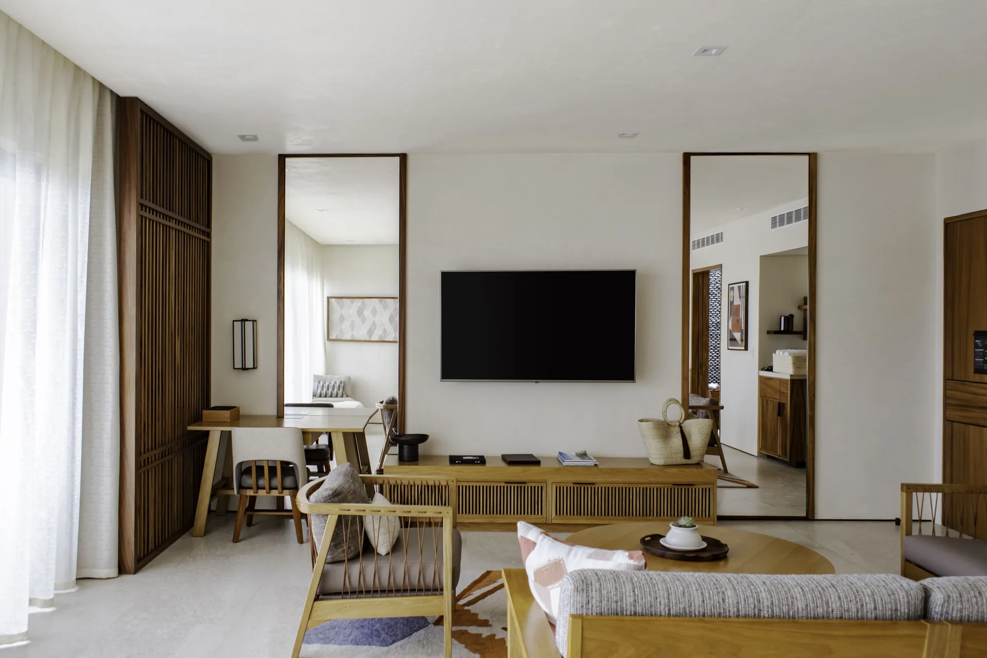 Junior Room living area with TV, desk, mirrors, and sofa at Nobu Hotel Los Cabos.