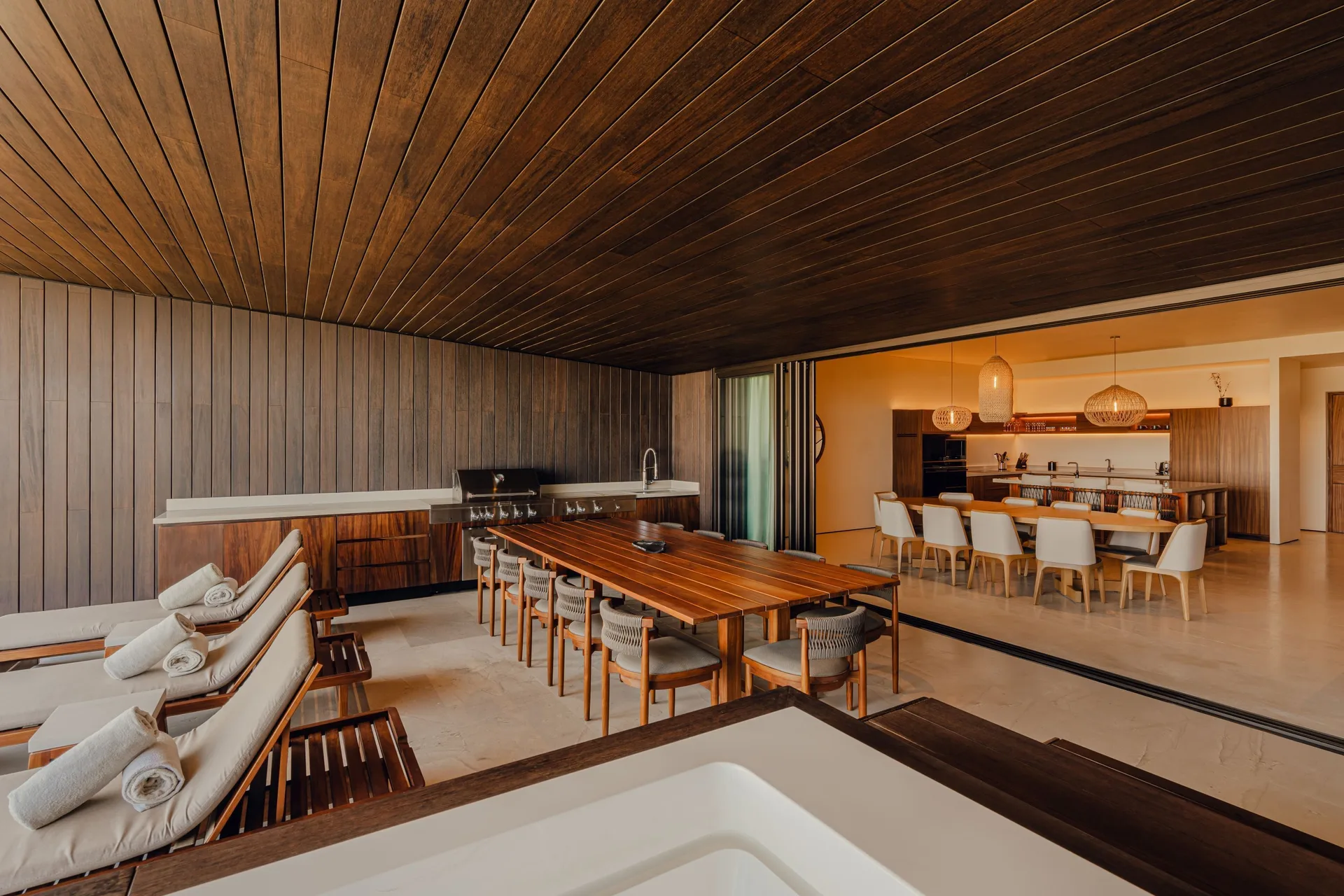 Terrace dining table, loungers, grill and indoor kitchen in Kogane Penthouse at Nobu Hotel Los Cabos.