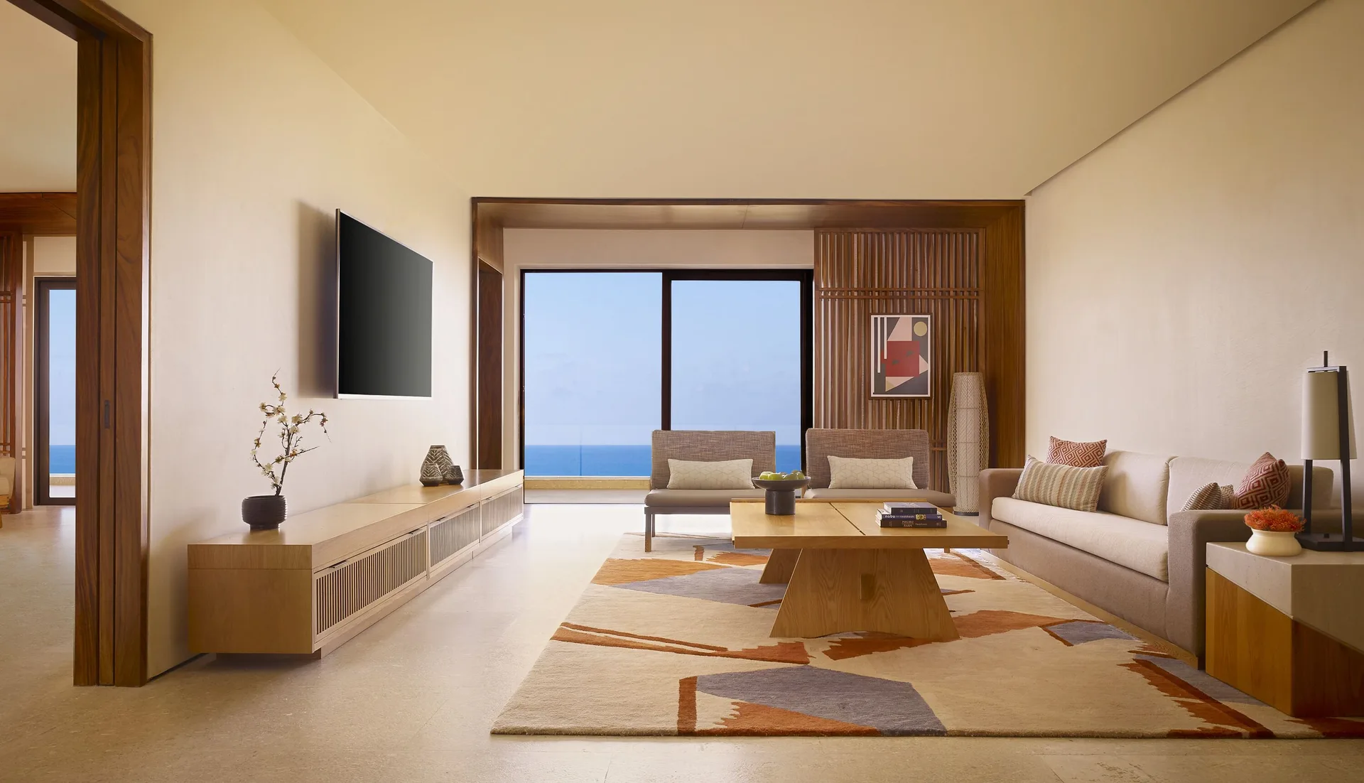 Ocean View Suite living room with sofa, chairs, and ocean-facing doors at Nobu Hotel Los Cabos.