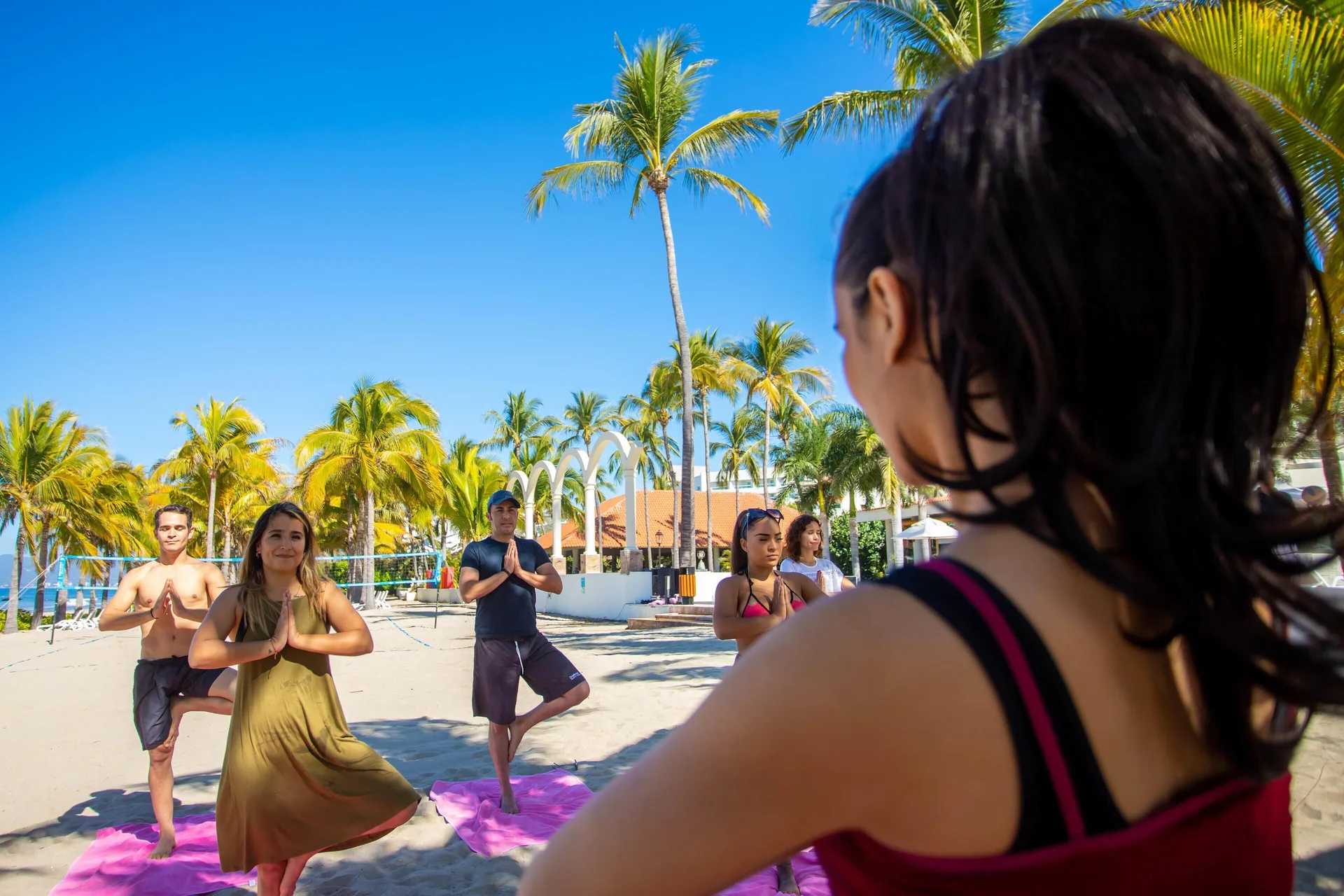 Guests practice beach yoga under palms at Occidental Nuevo Vallarta.