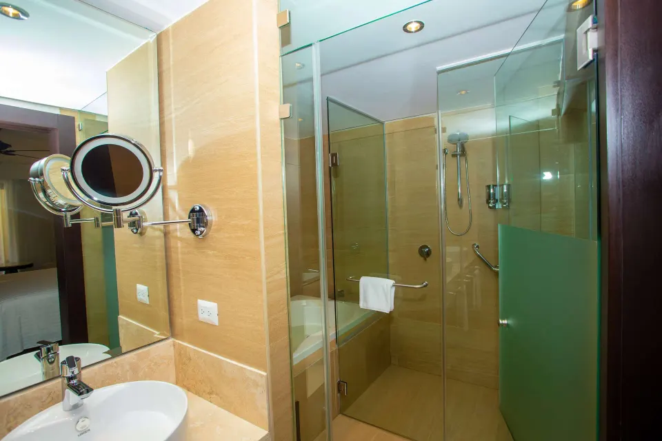 Junior Suite balcony bathroom with glass shower, sink, and wall mirror at Occidental Nuevo Vallarta.
