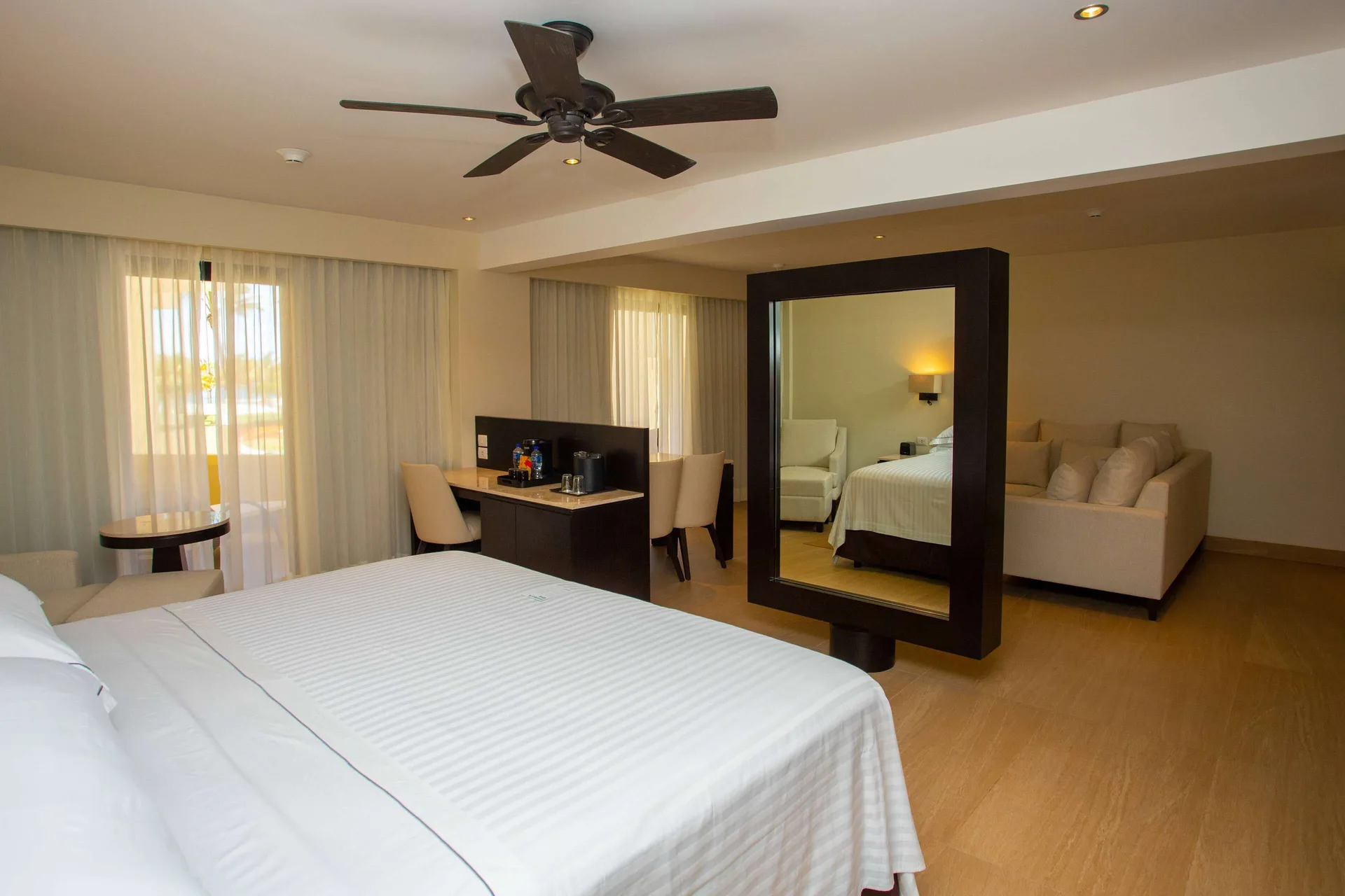 Junior Suite balcony room with king bed, desk, mirror, and sofa at Occidental Nuevo Vallarta.