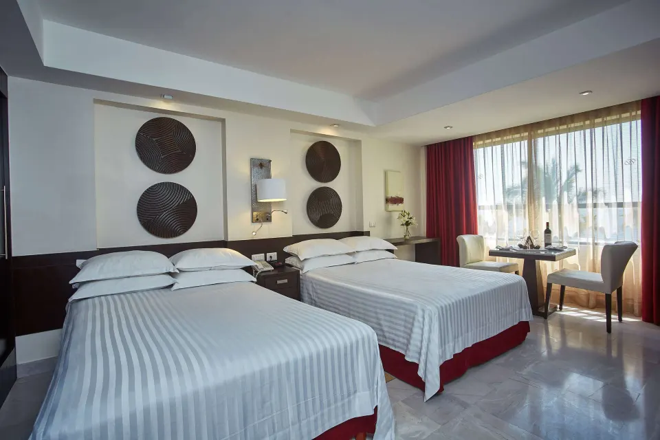 Royal Level luxury room with two beds and window seating at Occidental Nuevo Vallarta.