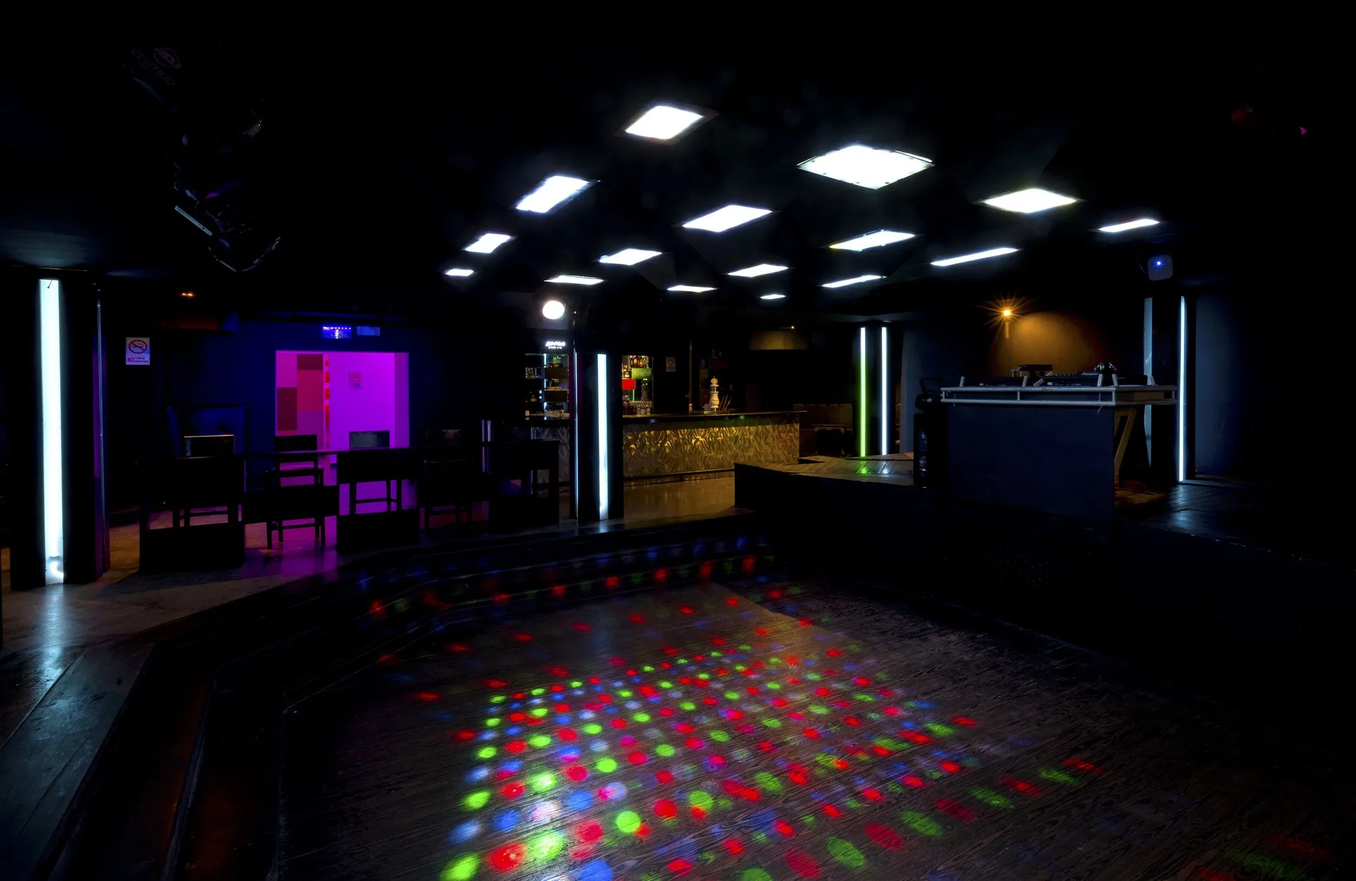 Dark nightclub dance floor with colored lights and DJ booth at Occidental Punta Cana.