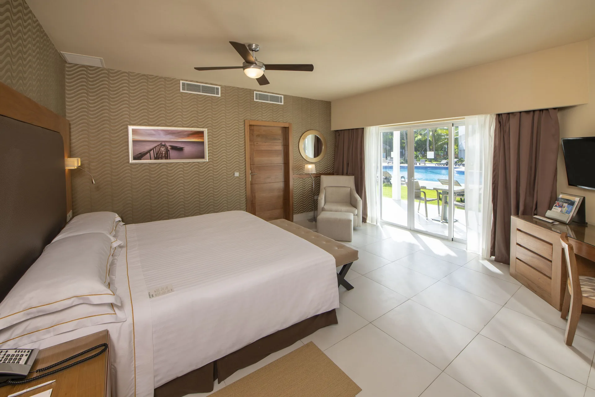 Royal Level Suite bedroom with king bed and poolside patio view at Occidental Punta Cana.