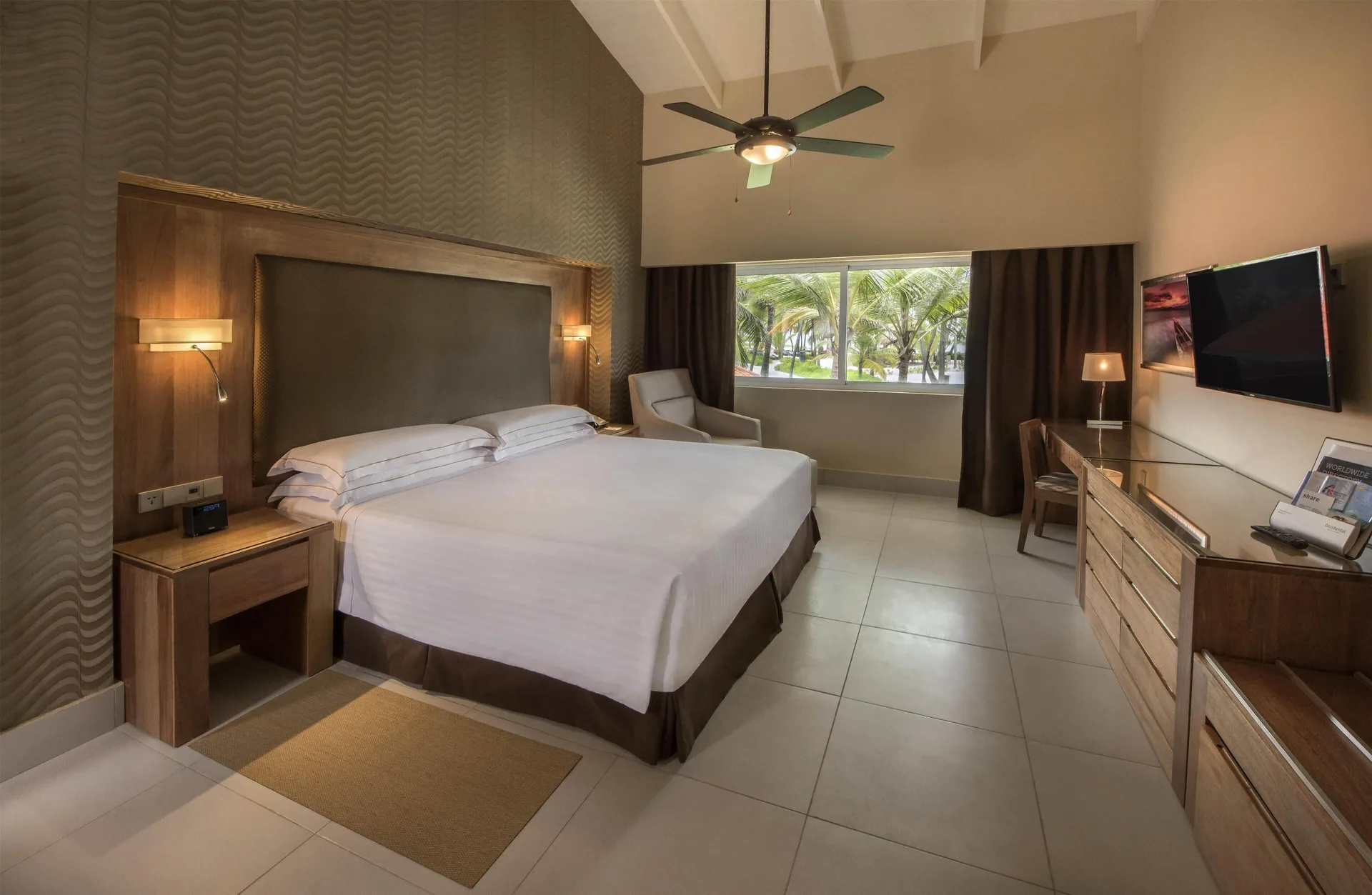 Royal Level Superior Room king bed with ceiling fan and dresser at Occidental Punta Cana.