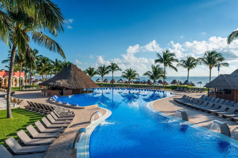 Large beachfront pool with loungers and palapa shade at Ocean Coral and Turquesa.