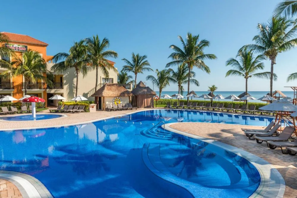 Curving blue pool with palms and ocean beyond at Ocean Coral and Turquesa.