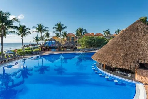 Poolside thatched swim-up bar beside blue water at Ocean Coral and Turquesa.