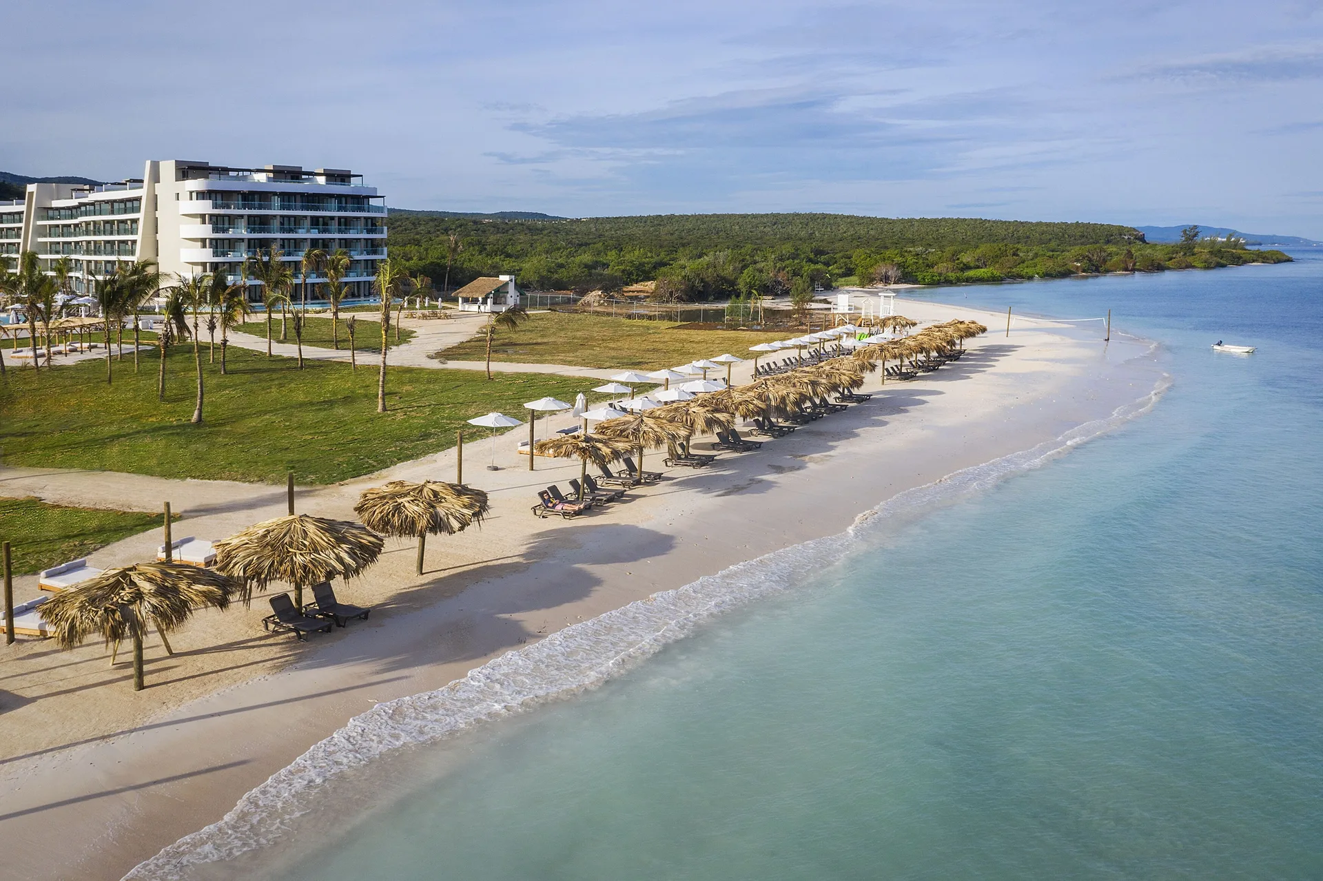 Aerial view of the beach, palapas, and resort building at Ocean Coral Spring.