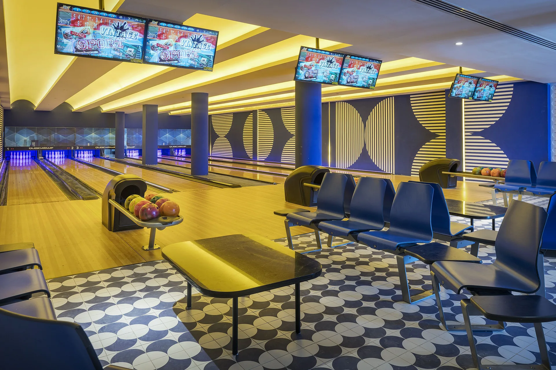 Bowling alley with lanes, blue seating and score screens at Ocean Coral Spring.