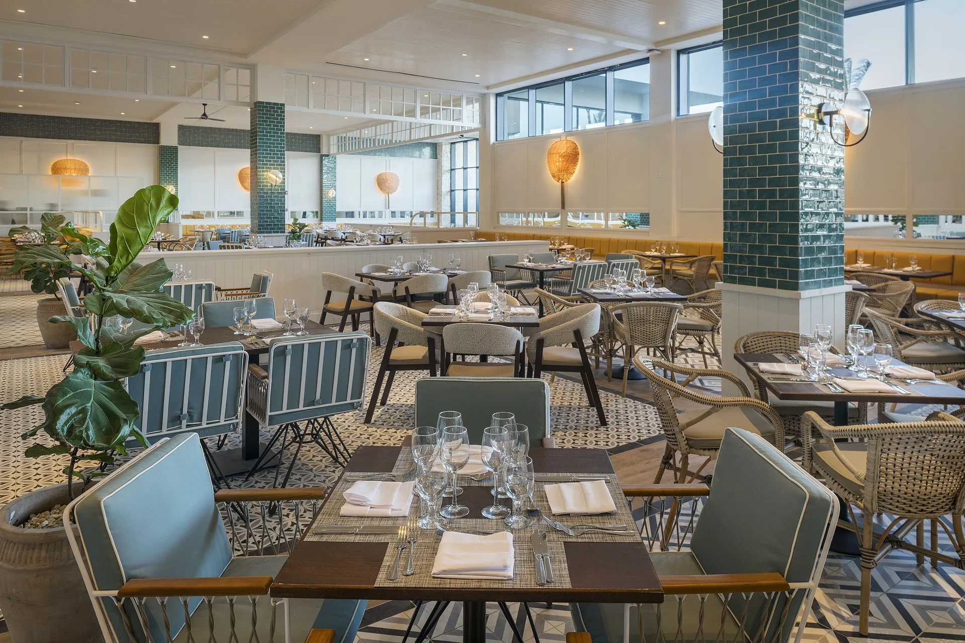 Restaurant seating with teal columns, potted plant and set tables at Ocean Coral Spring.