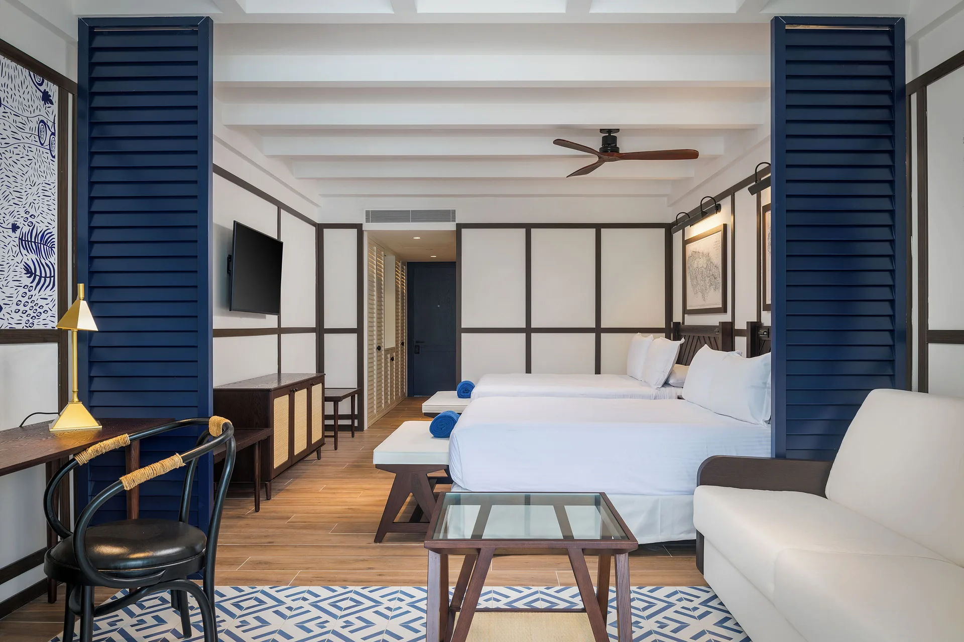 Junior Suite Nature View with twin beds, sofa, desk, and blue shutters at Ocean Coral Spring.