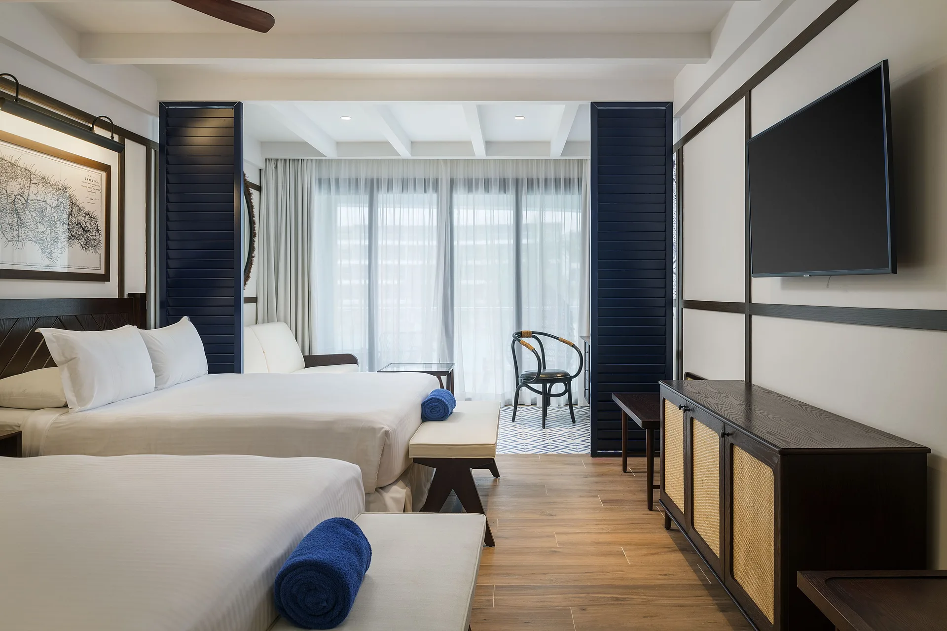 Junior Suite Nature View with two beds, TV, and curtained balcony doors at Ocean Coral Spring.