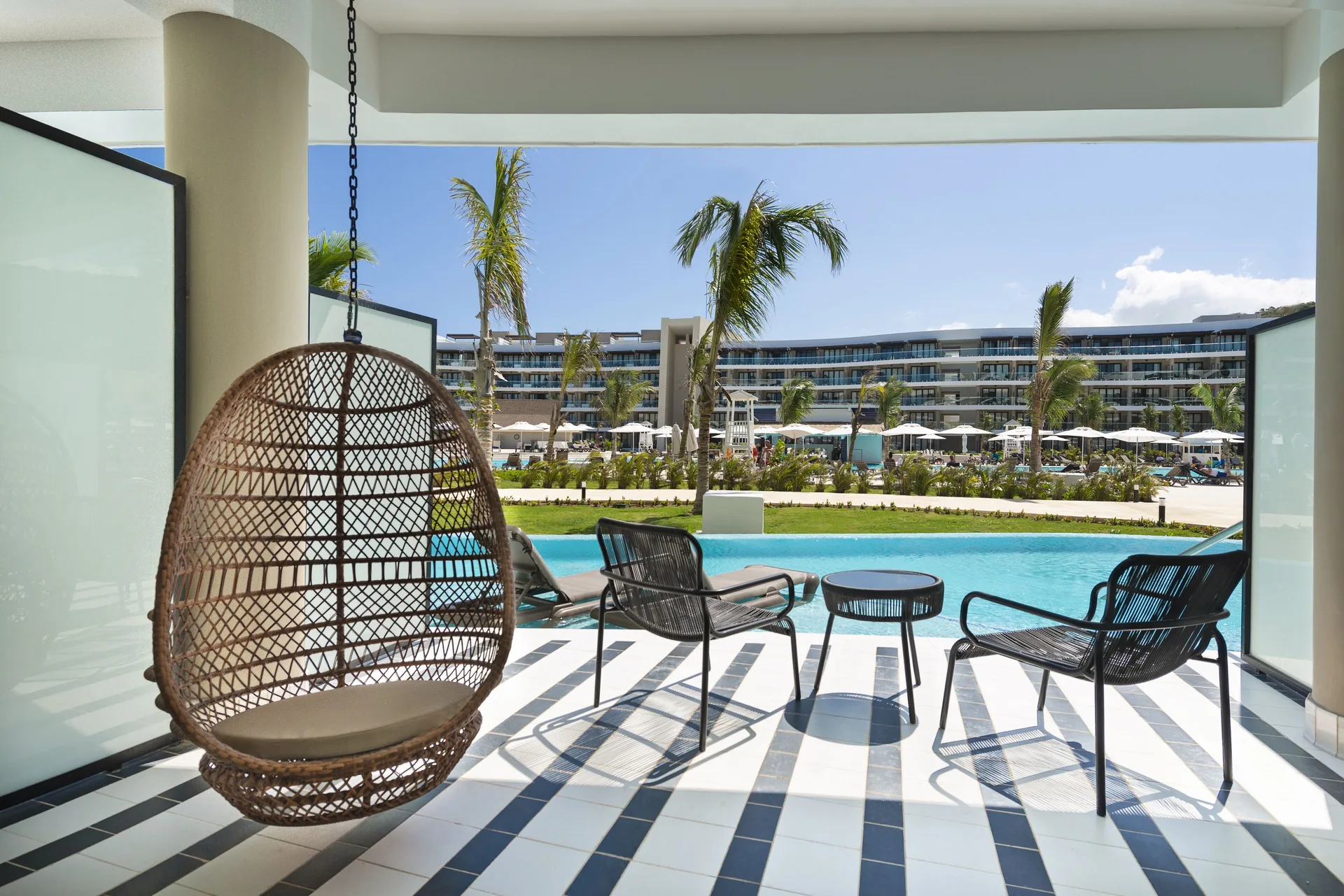 Junior Suite Swim Up patio with hanging chair and resort pool view at Ocean Coral Spring.