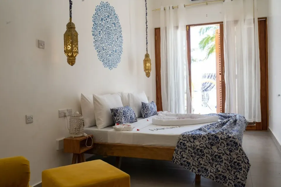Deluxe Apartment king bed with blue accents and balcony doors at Orient Beach Hotel.