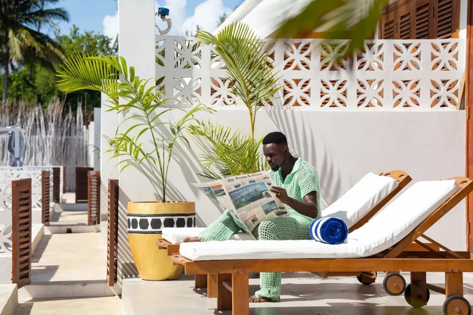 Terrace loungers with towels and potted palms at Orient Beach Hotel.
