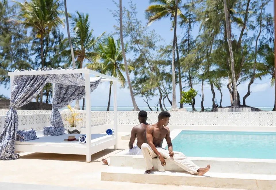 Private pool with cabana daybed, palm trees, and ocean beyond at Orient Beach Hotel.