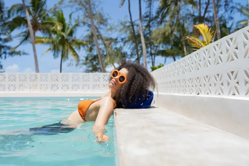 Guest relaxing in a private pool bordered by white screen walls at Orient Beach Hotel.