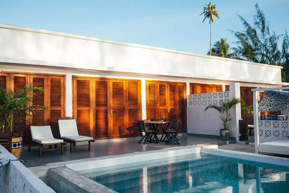 Private pool patio with loungers and wooden shutters at Orient Beach Hotel.