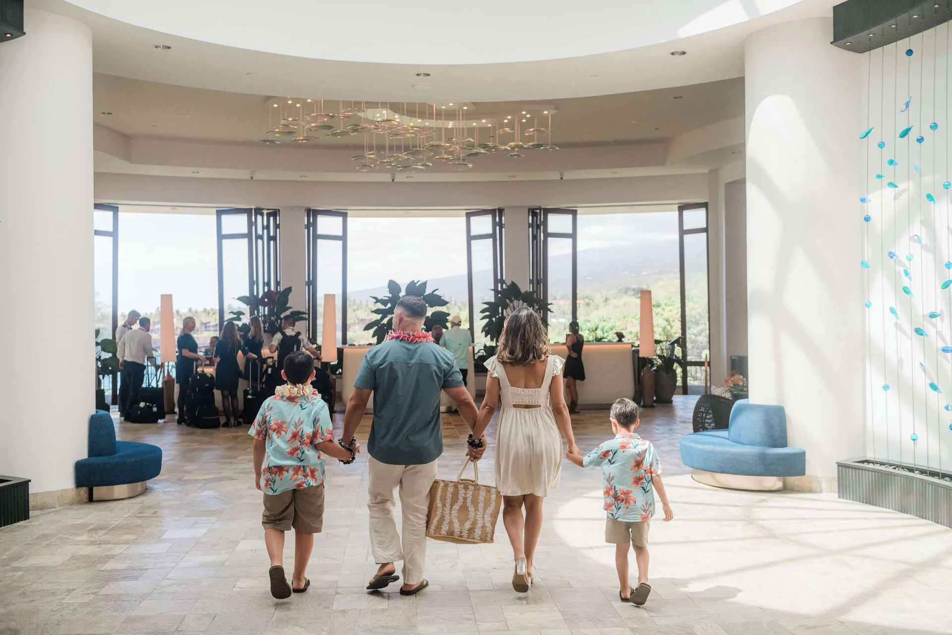 Family walking through the sunlit lobby at Outrigger Kona Resort and Spa.