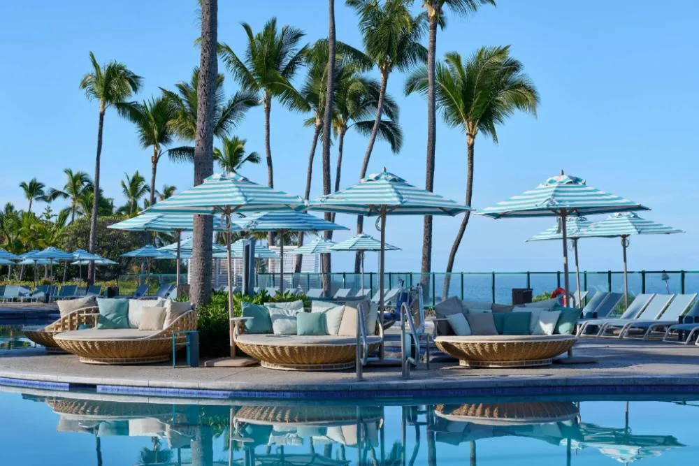 Poolside seating with umbrellas and ocean beyond at Outrigger Kona Resort and Spa.
