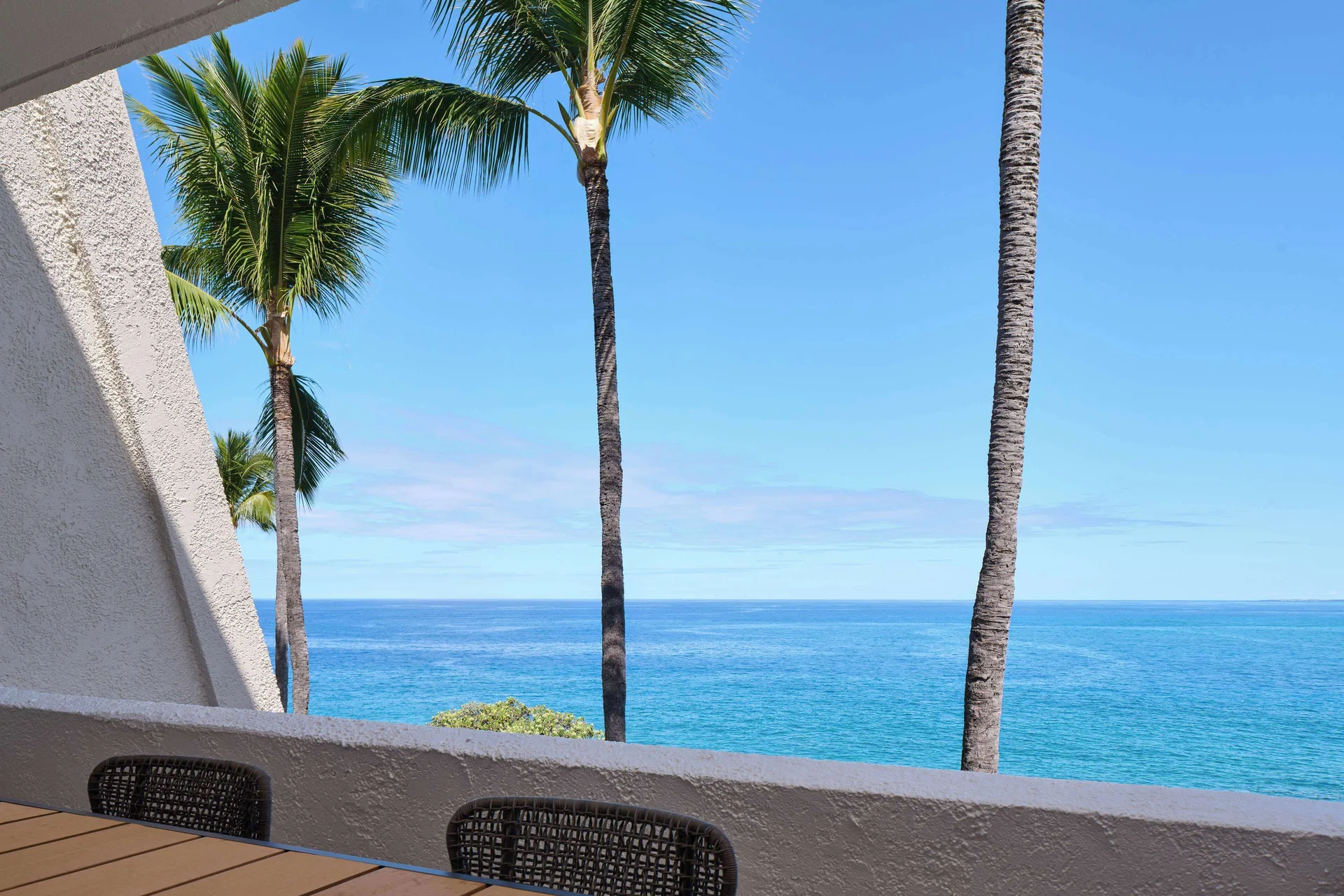 Oceanfront balcony with palm trees and blue water at Outrigger Kona Resort and Spa.