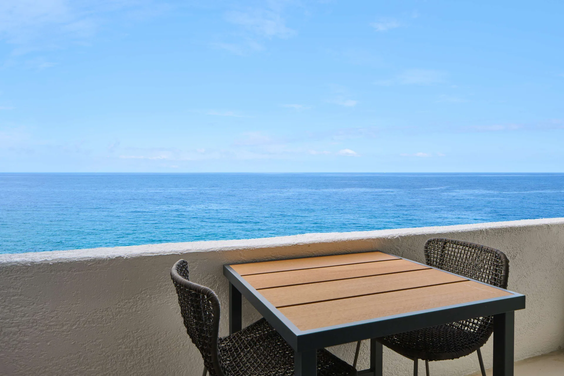 Oceanfront balcony table and chairs overlooking the water at Outrigger Kona Resort and Spa.