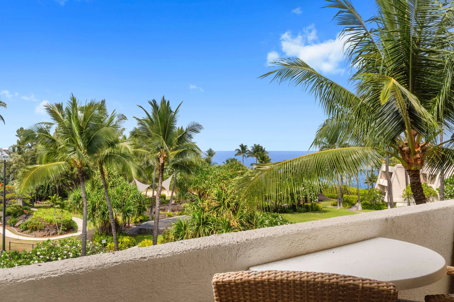 Balcony with palm trees and ocean beyond a resort view room at Outrigger Kona Resort and Spa.