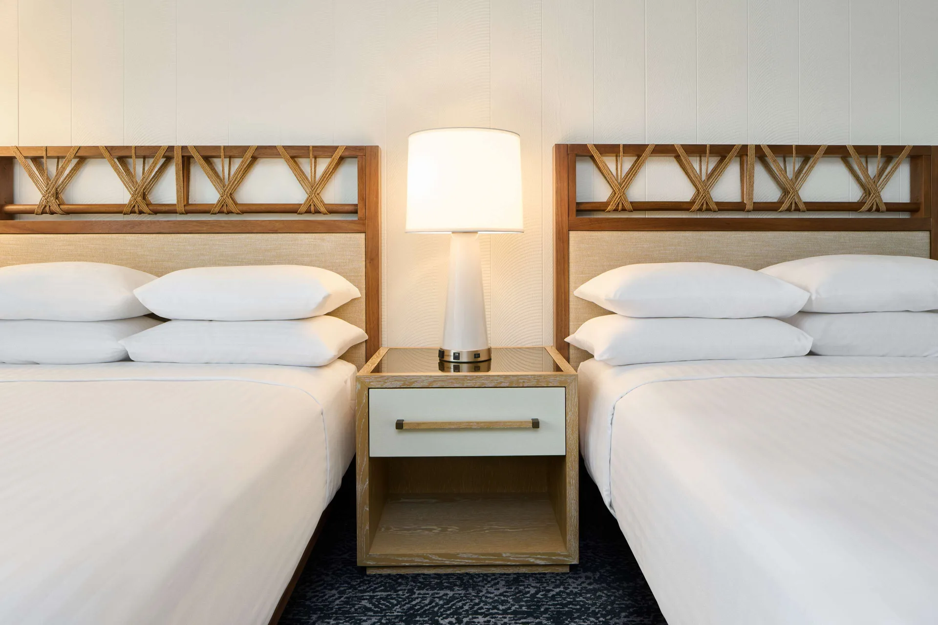 Two white beds with woven headboards in a resort view room at Outrigger Kona Resort and Spa.