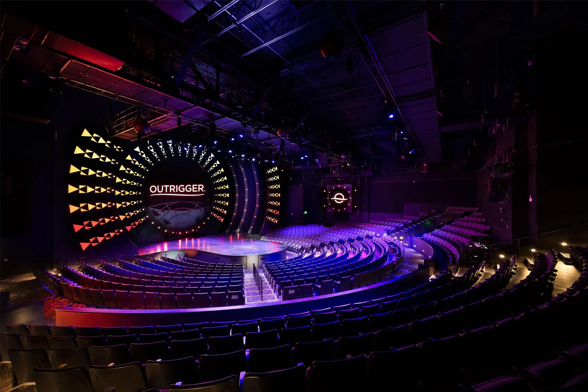 Large theater with curved seating and illuminated stage at OUTRIGGER Waikiki Beachcomber Hotel.