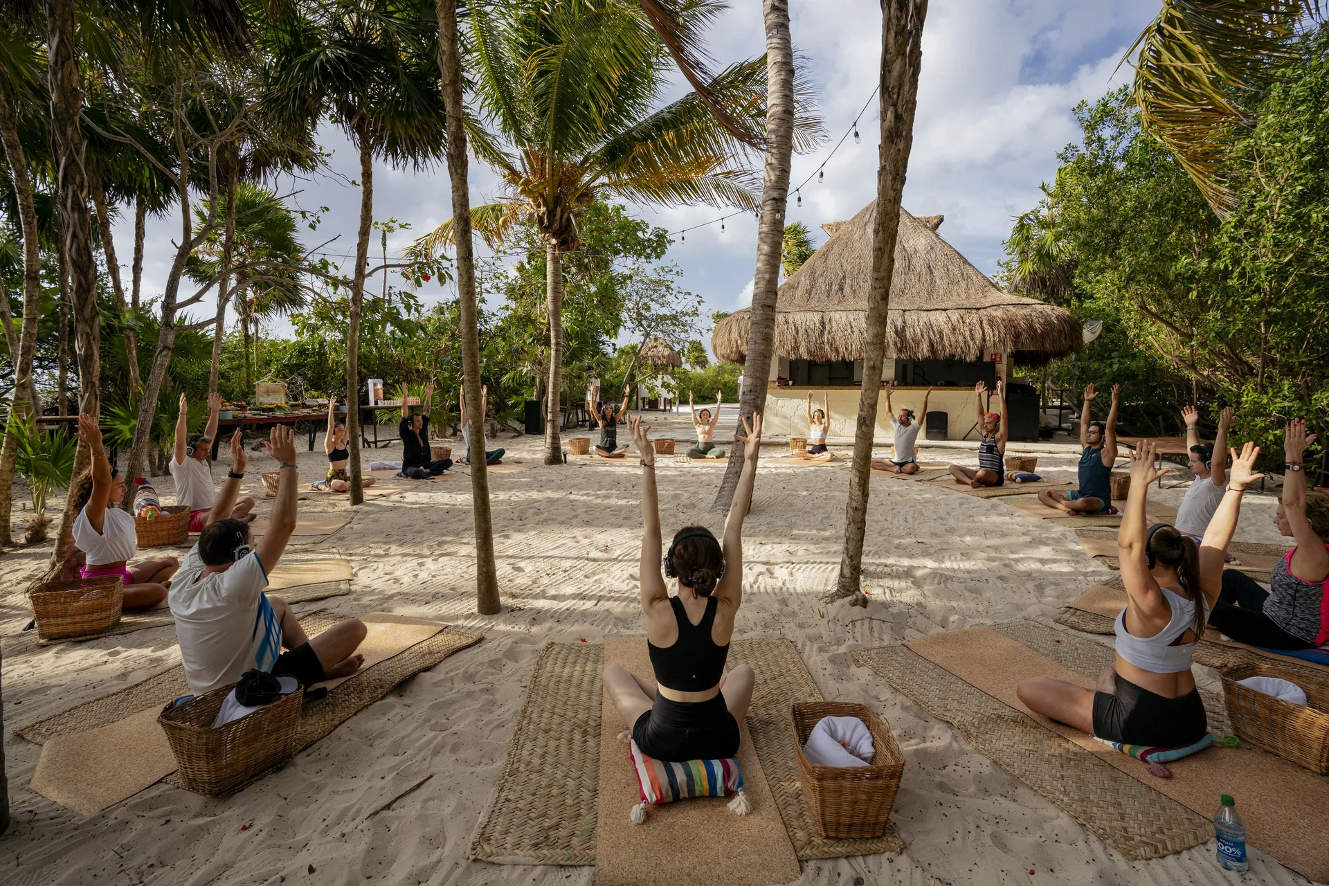 Beach yoga class on sand among palm trees at Paradisus La Perla Riviera Maya.