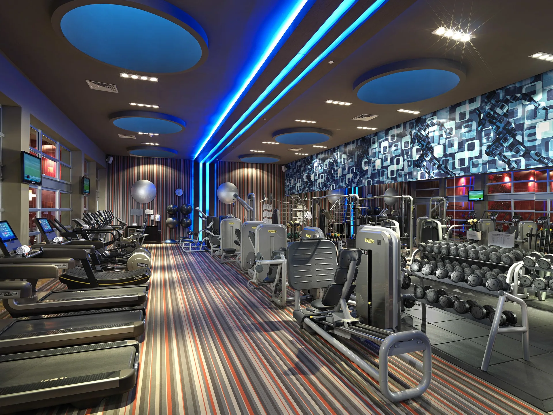 Fitness center with cardio machines, weights, and blue ceiling lights at Paradisus La Perla Riviera Maya.