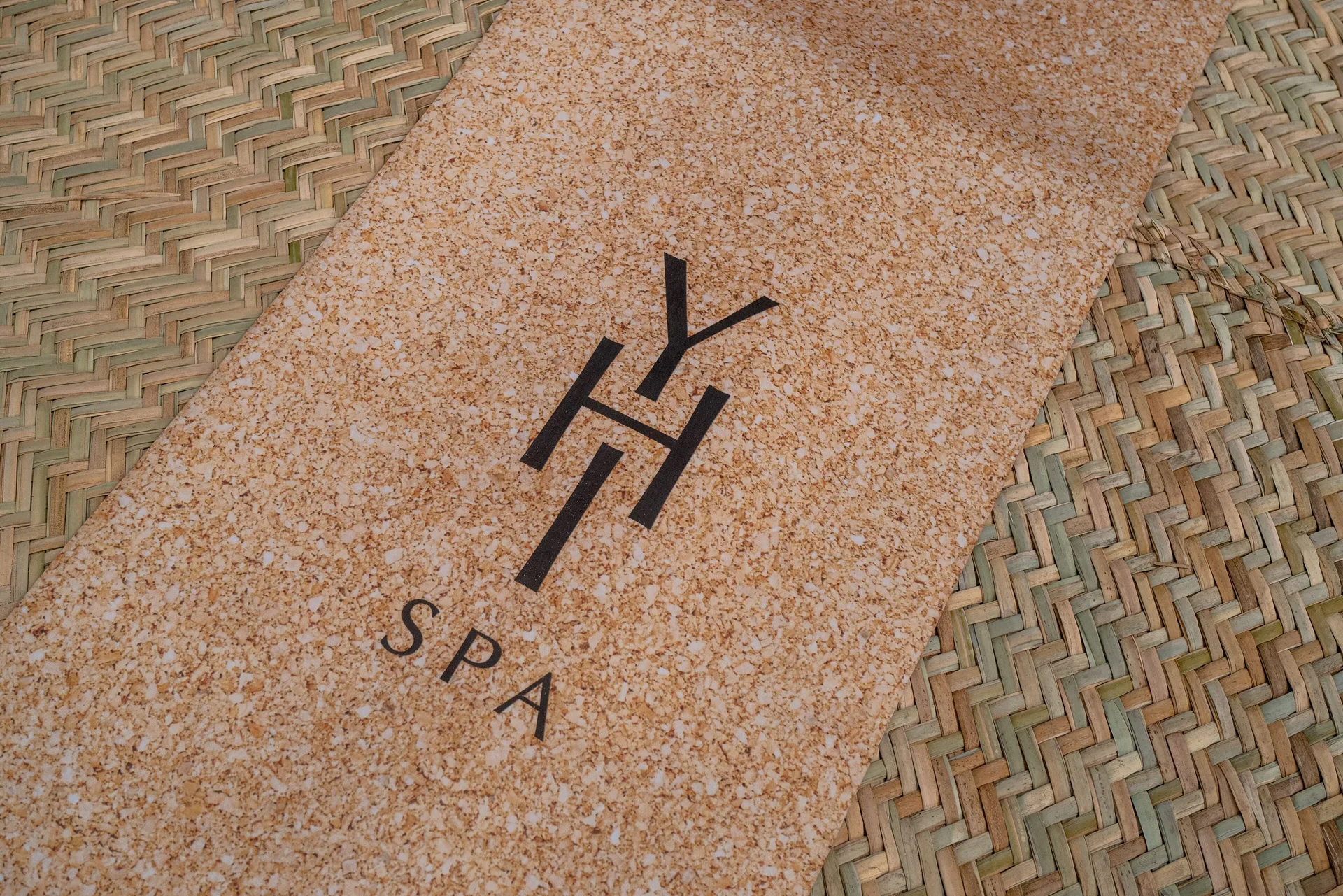 A spa mat with a printed spa logo rests on woven flooring at Paradisus La Perla Riviera Maya.