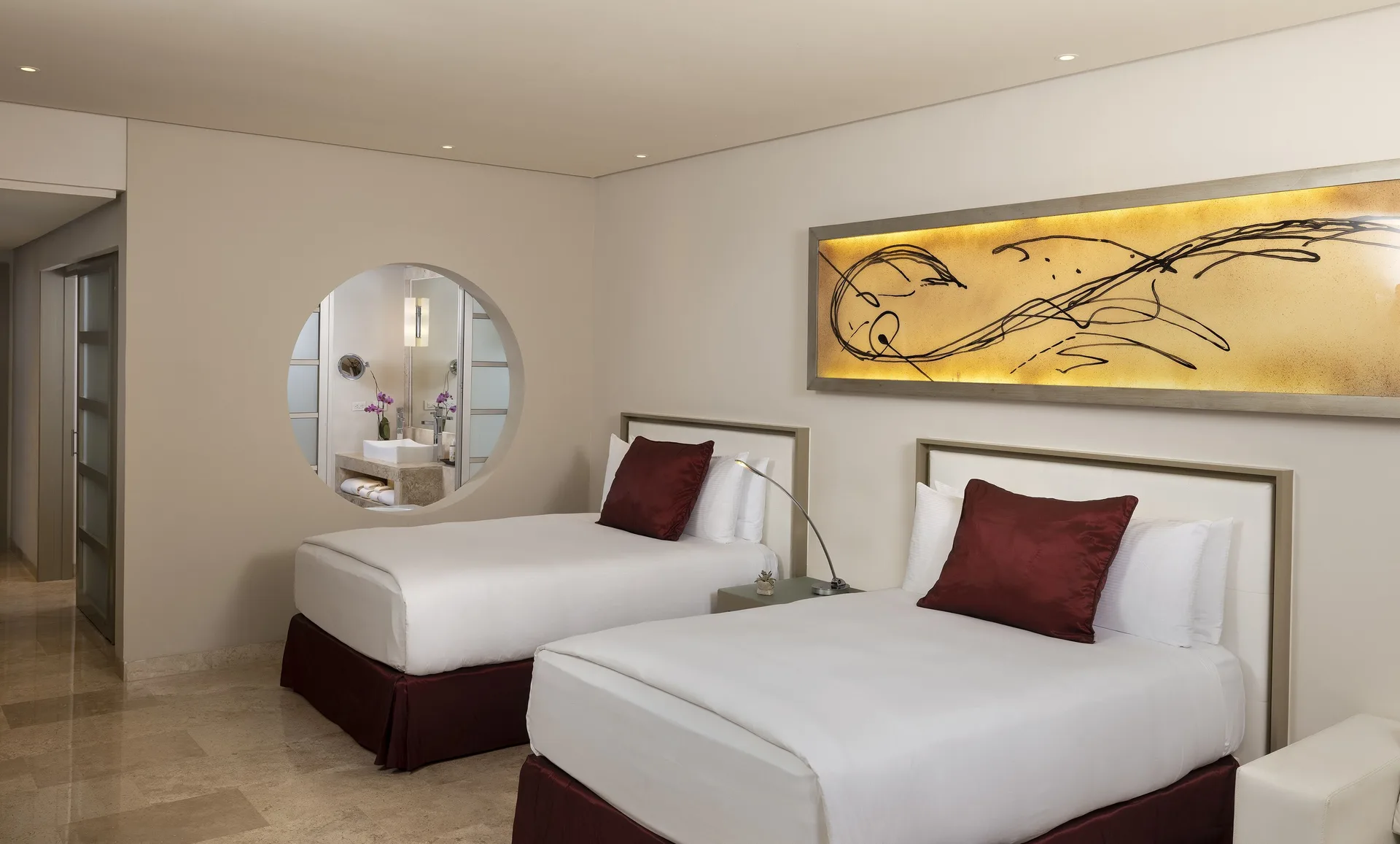 Two double beds with burgundy pillows in a guest room at Paradisus La Perla Riviera Maya.