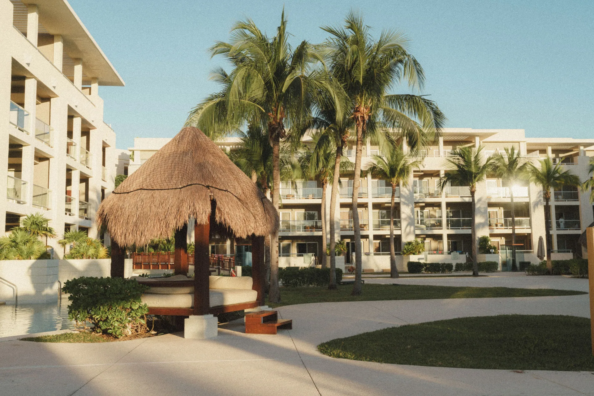 The Reserve Nature View exterior with palms and a thatched daybed at Paradisus La Perla Riviera Maya.