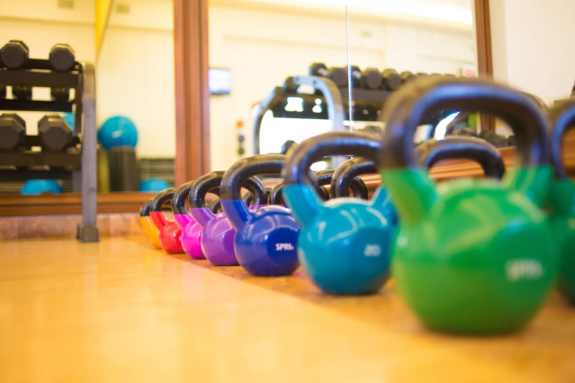 Colorful kettlebells lined up on a gym floor at Playa Grande Resort & Grand Spa.