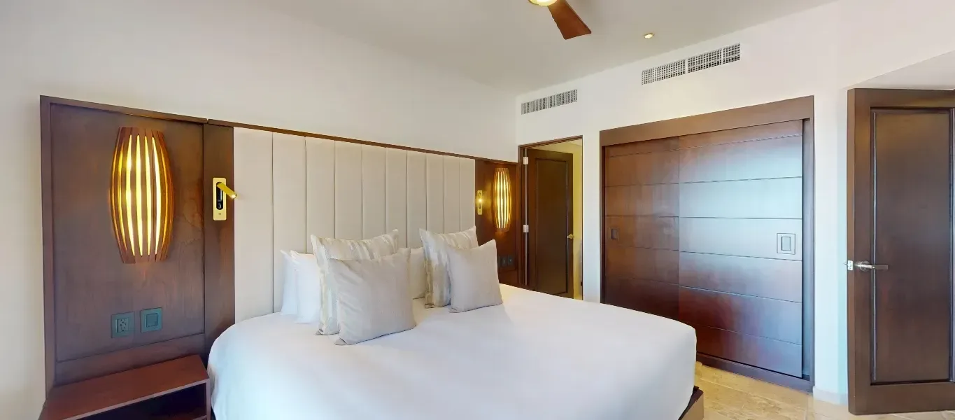 Junior Suite De Luxe king bed and wood-paneled headboard at Playa Grande Resort & Grand Spa.