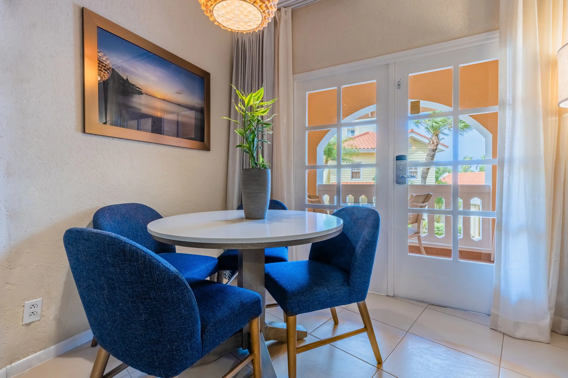 Dining nook with round table, blue chairs and balcony doors at Playa Linda Beach Resort.