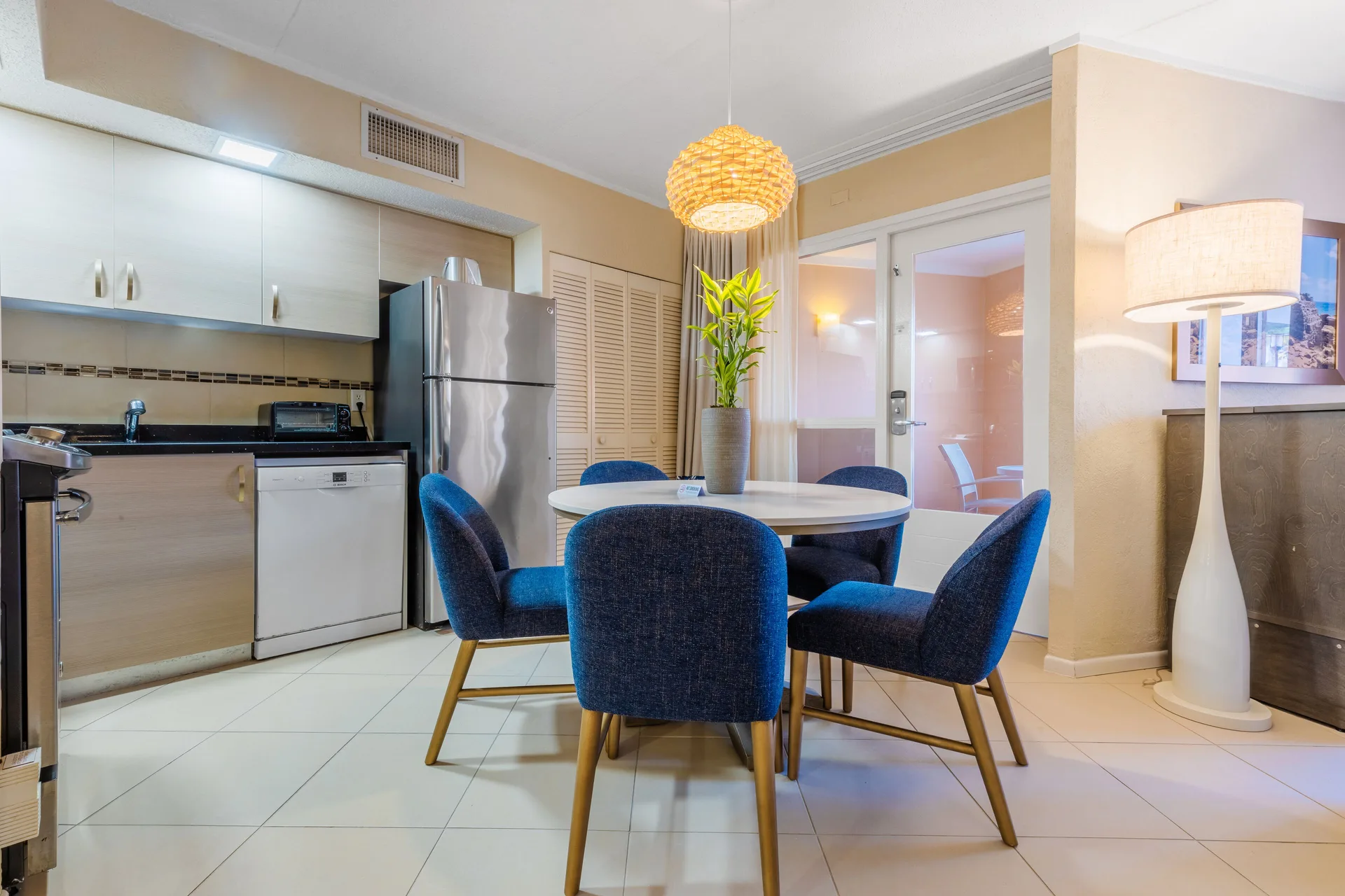 Guest room dining area with round table, blue chairs and kitchenette at Playa Linda Beach Resort.