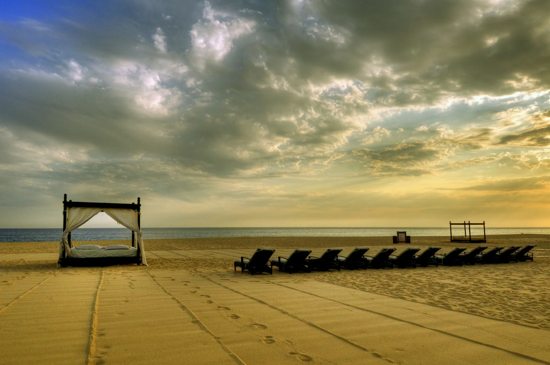 Beach loungers and a daybed under a dramatic sky at Pueblo Bonito Pacifica Golf & Spa Resort.