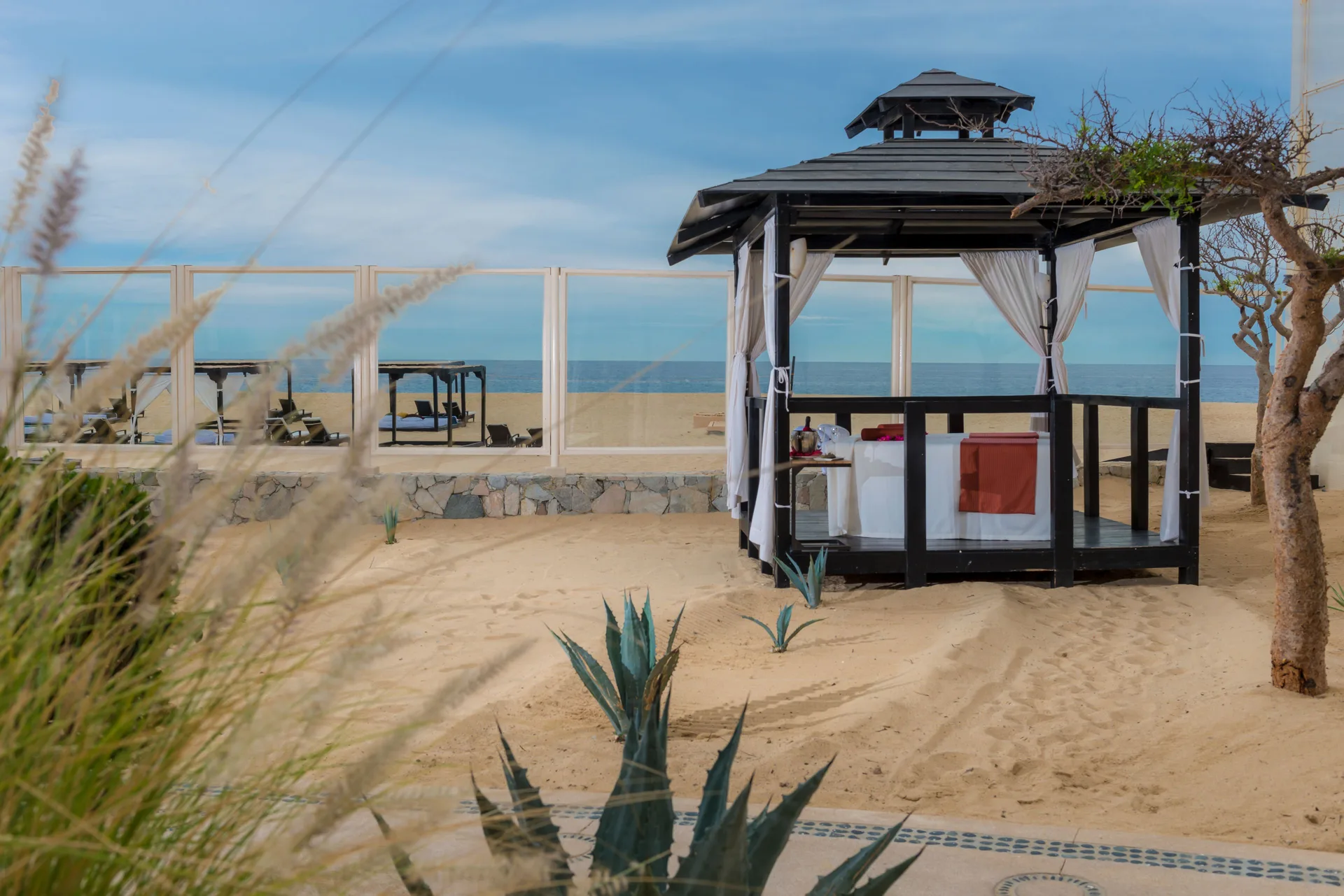 Beachfront spa cabana with curtains and a treatment table on the sand at Pueblo Bonito Pacifica Golf & Spa Resort.