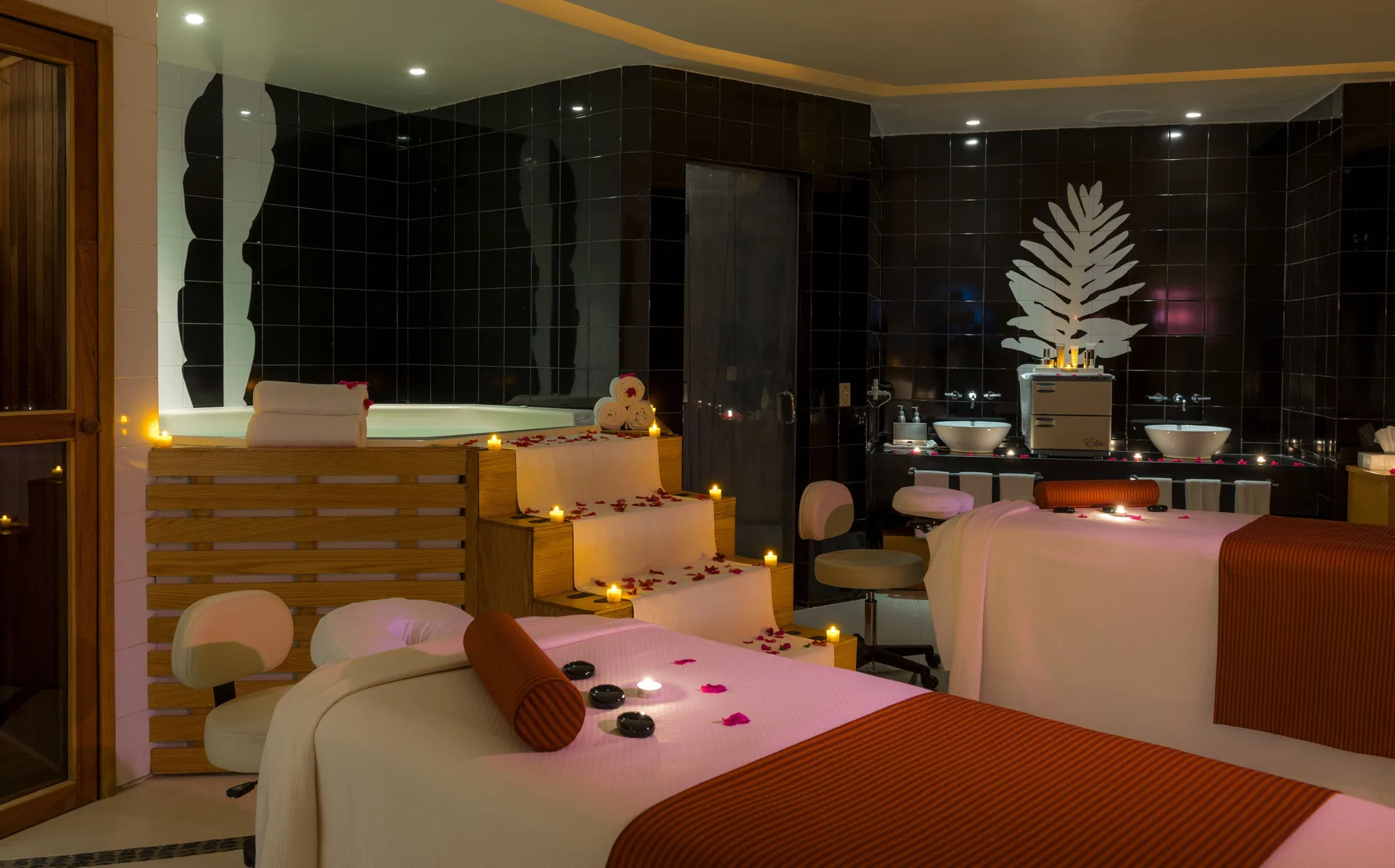 Candlelit spa treatment room with massage tables, soaking tub, and black tile walls at Pueblo Bonito Pacifica Golf & Spa Reso