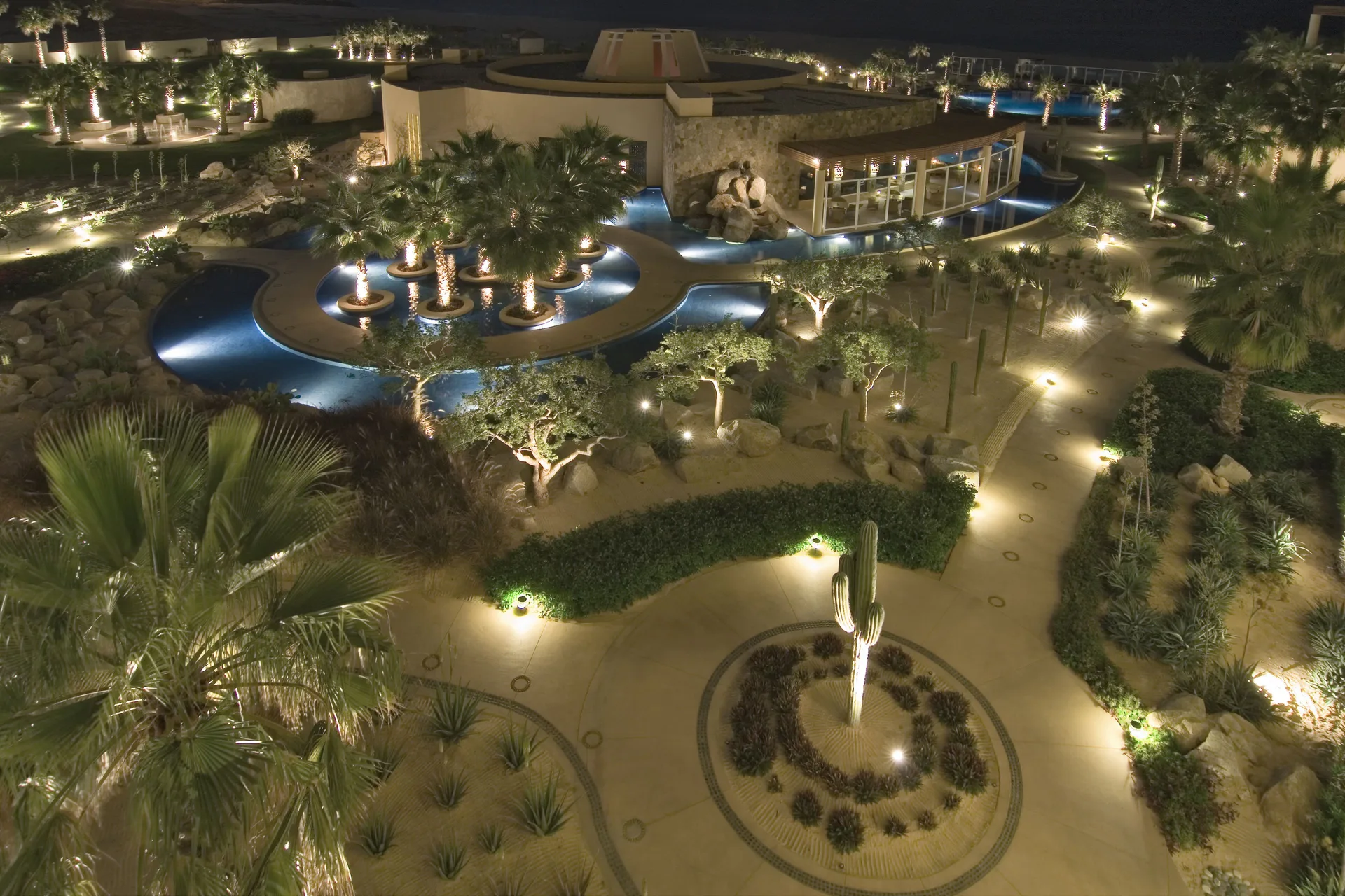 Illuminated pools, palms, and garden paths at night at Pueblo Bonito Pacifica Golf & Spa Resort.